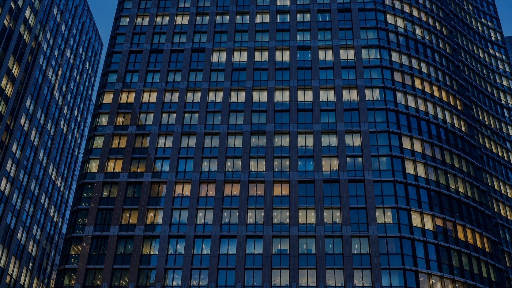 Fassade eines modernen Bürohochhauses zur blauen Stunde
